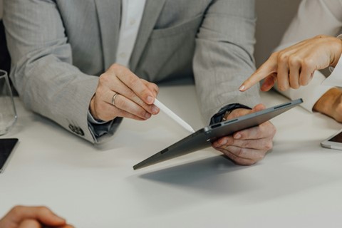 personer pekar på en surfplatta