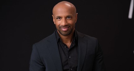 Man i skjorta och kavaj framför svart backdrop