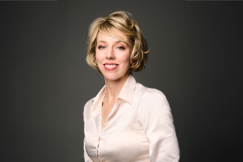 Person i ljus långärmad skjorta mot mörk enfärgad bakgrund