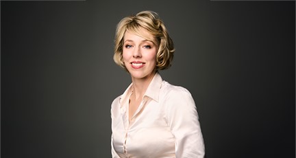 Person i ljus långärmad skjorta mot mörk enfärgad bakgrund