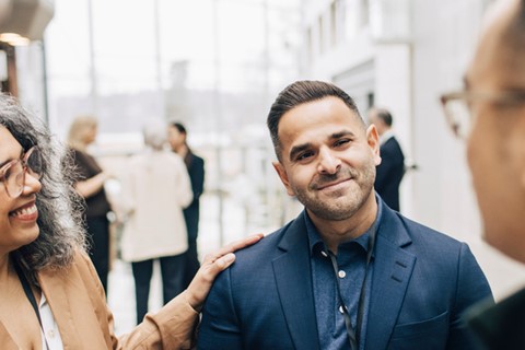 Leende, avslappade kollegor står i grupp och pratar