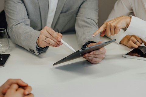 Händer på personer i möte, håller i en ipad och diskuterar