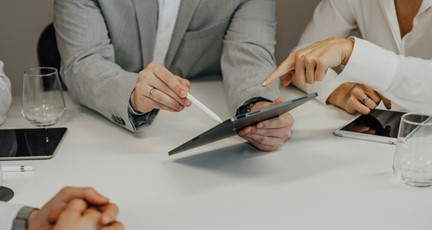 Händer på personer i möte, håller i en ipad och diskuterar