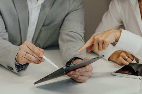 Två personer tittar och pekar på en surfplatta