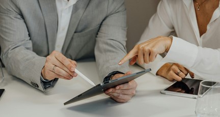 Två personer tittar och pekar på en surfplatta