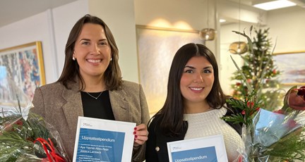 två stipendiater med blommor och diplom