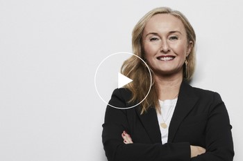 Leende kvinna i svart kavaj tittar mot kameran