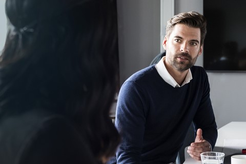 Finansförbundet-fackförbund Man sitter på kontor framför laptop och pratar med en kollega