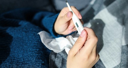 Person håller febertermometer framför sig