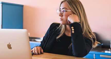 Kvinna funderar vid laptop