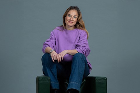 Magdalena Kowalczyk Leende kvinna sitter på ryggtstödet i en fåtölj, tittar mot kameran
