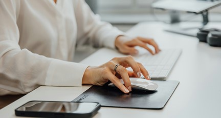 Närbild på skrivbord med datormus, tangentbord och smartphone