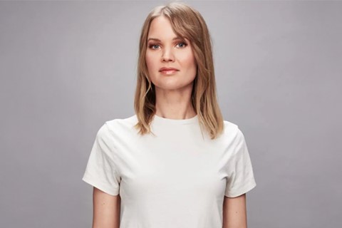 Kvinna i vit t-shirt tittar mot kameran