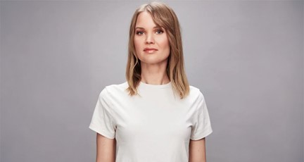 Kvinna i vit t-shirt tittar mot kameran