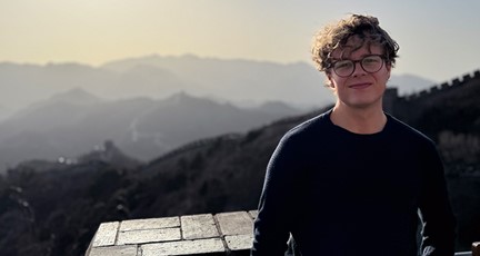 Man med glasögon, står på Kinesiska muren i kvällsljus